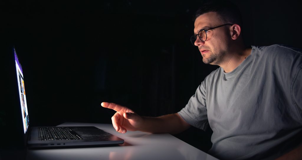 Молодий чоловік читає error log сервера вночі за комп'ютером