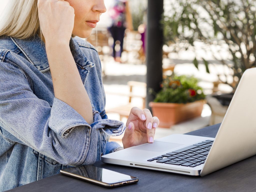 Жінка пише тікет у техпідтримку хостингу з ноутбука та смартфона